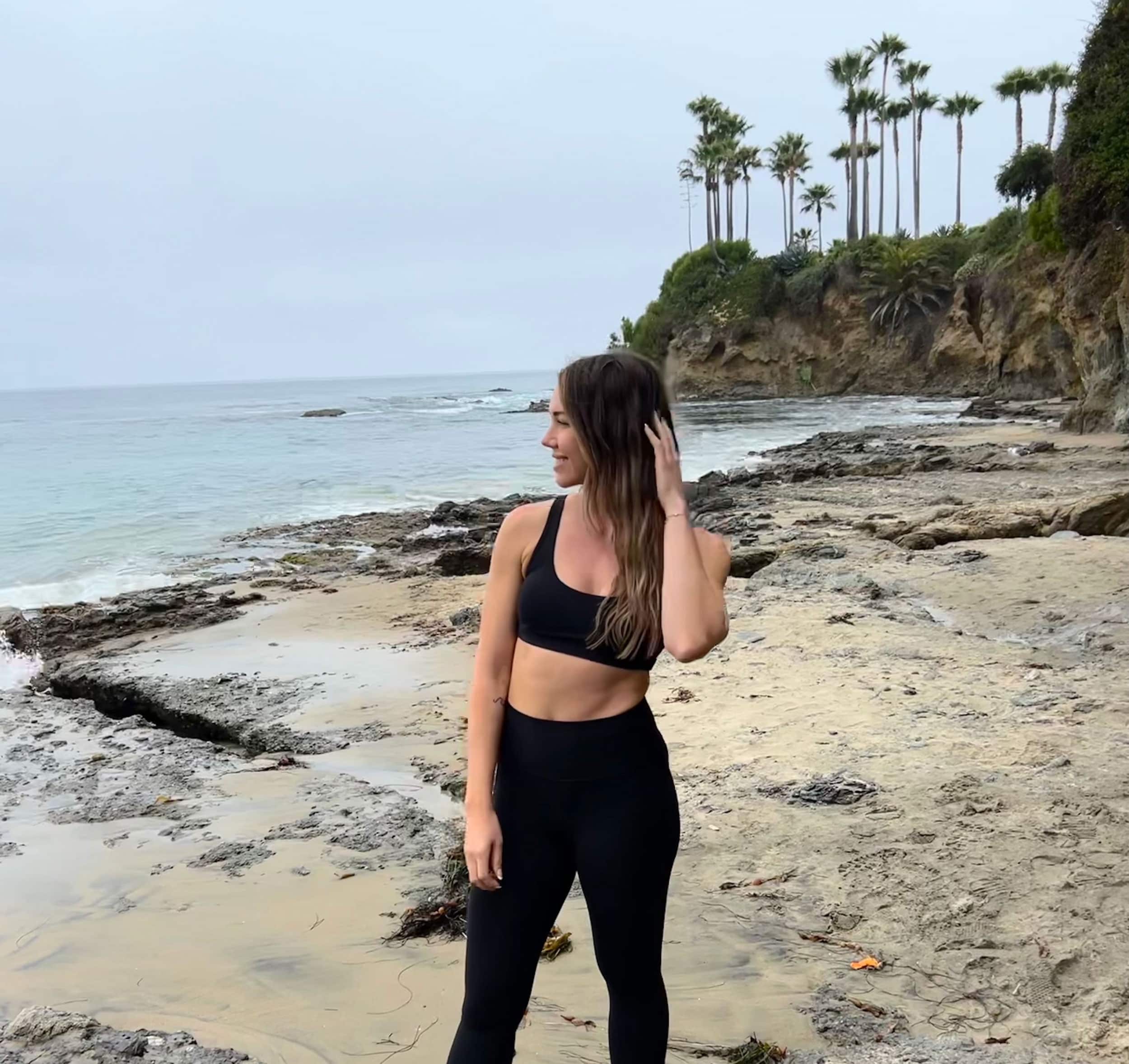 Coach Tiff posing on a beach wearing a workout outfit